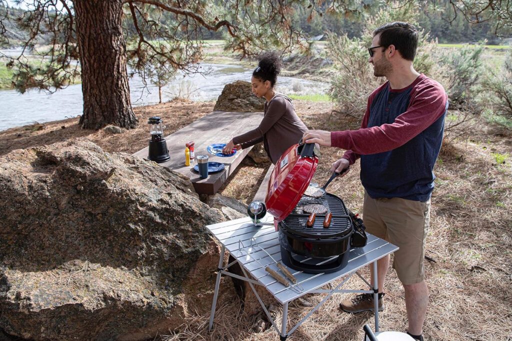 Coleman RoadTrip 225 Portable Tabletop Propane Grill in a vibrant outdoor setting, showcasing its compact design and powerful grilling features, perfect for camping, tailgating, and outdoor cooking adventures.